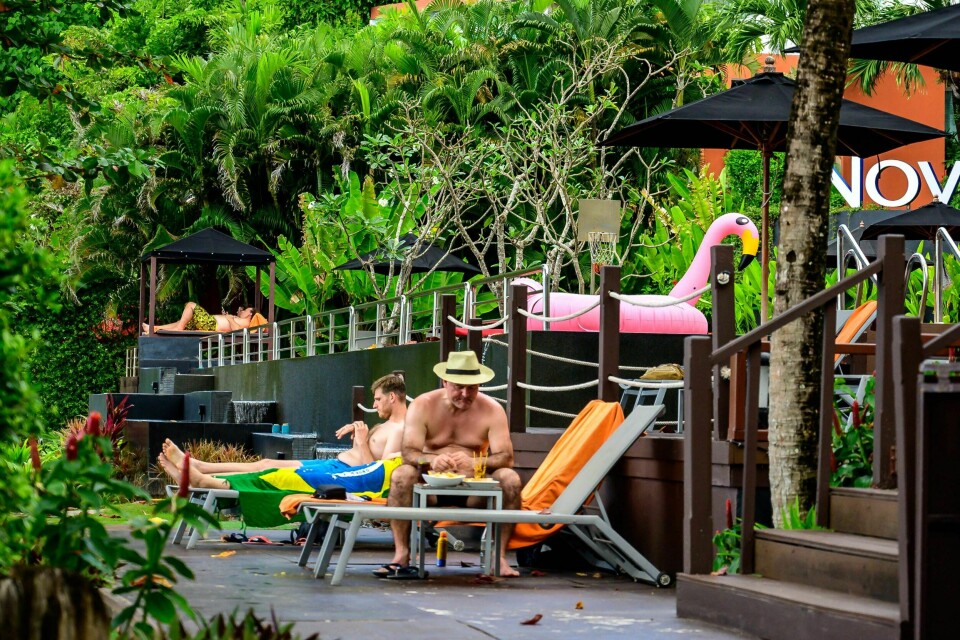 REISE: Nå kan du reise til Thailand. Er du i tillegg fullvaksinert og kan vise en negativ koronatest, slipper du også karantene. Mann sitter på solseng. Rundt han er det masse palmer og grønneomgivelser.