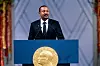 Bildet er av Abiy Ahmed som står på en talerstol da han vant Nobels fredspris. Han har på dress. Talerstolen er blå, med et stort merke i samme form og design som Nobelpris-medaljen. Foto: Stian Lysberg Solum / NTB
