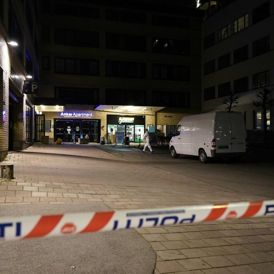 DØD: En person er funnet død i Oslo onsdag morgen. Bildet er av en murbygning med en steinlagt plass foran. I forgrunnen er et sperrebånd fra politiet. Politi i hvite drakter driver med etterforskning på stedet. De har også en hvit kassebil. Foto: Terje Bendiksby / NTB