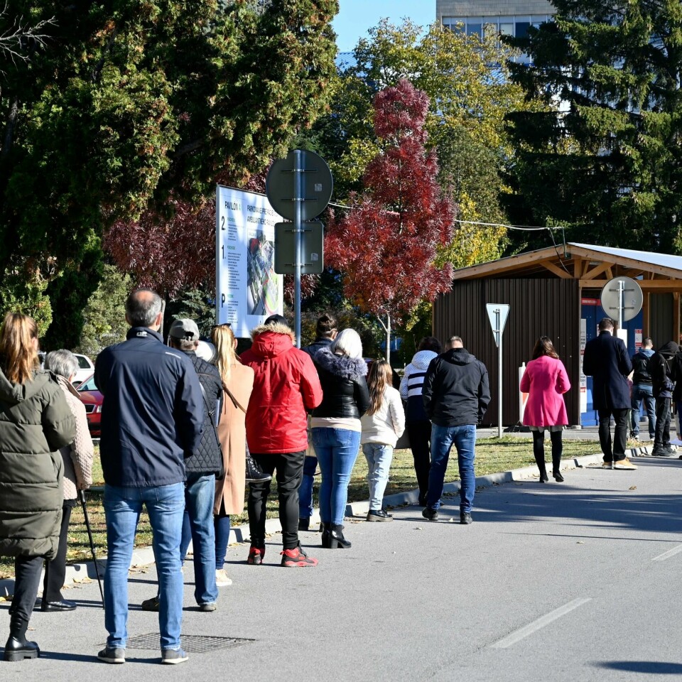 REKORD: Aldri før er så mange smittet med korona i Slovakia. Bildet er av folk som står utendørs langs en vei i Slovakia. De venter på å få teste seg for korona. I bakgrunnen er det trær. Foto: Roman Hanc / TASR / AP / NTB