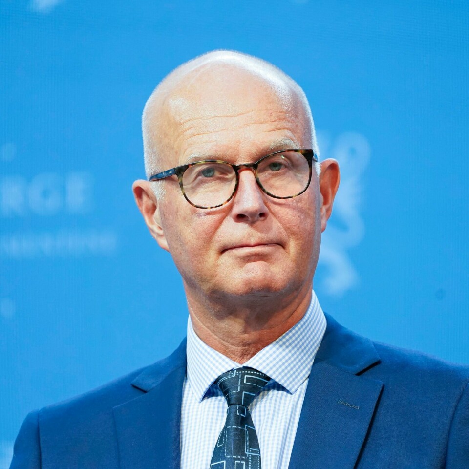 FLERE: Bjørn Guldvog tror det kan bli behov for mer enn tre doser med korona-vaksine. Han mener det kan komme en fjerde dose som følge av omikron-varianten. Bildet er av helsedirektør Bjørn Guldvog. Han har på dress, briller og står foran en blå vegg.
