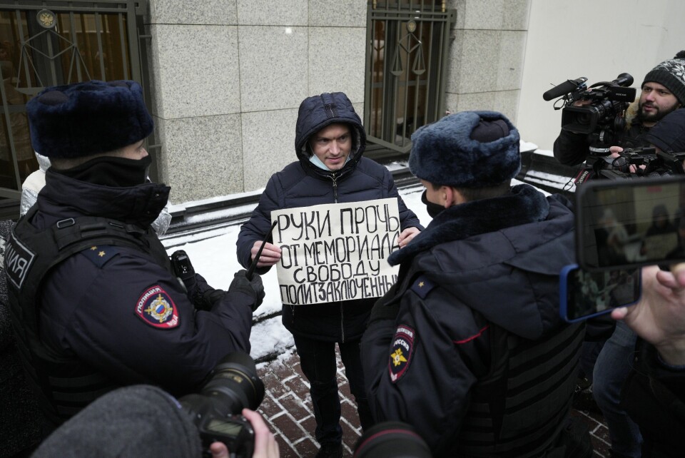 AKTIVIST: En aktivist står utenfor rettsalen med et skilt der det står «frihet for politiske fanger». Han ble senere arrestert. Demonstranter protesterte torsdag utenfor rettsbygningen i Moskva, mot påtalemyndighetens forsøk på å forby landets eldste menneskerettsgruppe Memorial. Foto: AP / NTB