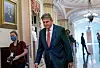 Bildet er av senator Joe Manchin. Han er i en korridor inne i kongressbygningen i USA. Det er fotografer med munnbind rundt ham. Manchin har på seg dress, men ikke noe munnbind. Foto: J. Scott Applewhite / AP / NTB