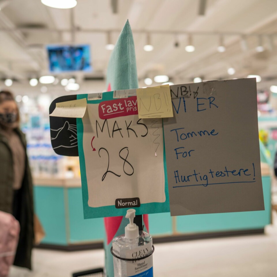 MER: Folk handler mer til jul i år enn i fjor. Bildet er av to personer inne på en Normal-butikk. Det er et skilt som sier det er en øvre grense på 28 kunder samtidig. Det er også en flaske håndsprit ved inngangen. Foto: Heiko Junge / NTB