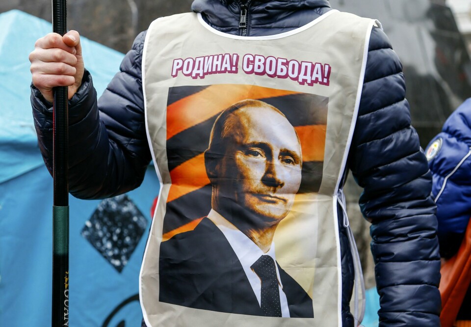 KONFLIKT: Russland har sendt soldater inn til Ukraina. Her er en person som støtter Vladimir Putin under en demonstrasjon i Donetsk i 2014. En prorussisk demonstrant i Donetsk mandag kveld. «Moderlandet! Frihet»» lyder teksten på vesten hans, som prydes av et foto av president Vladimir Putin. Foto: AP / NTB