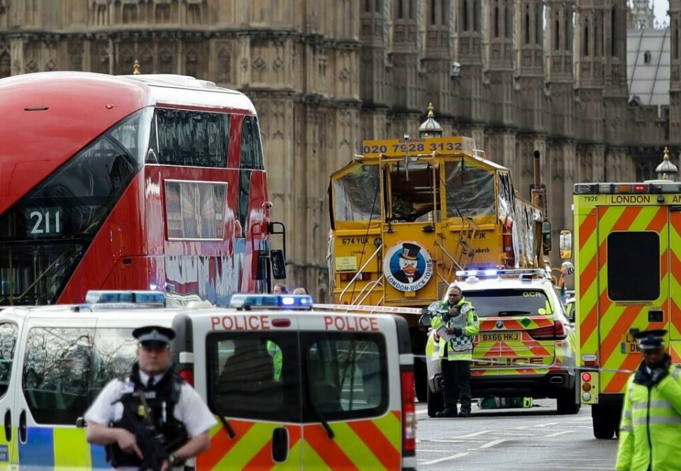 VÅPEN: Politiet vokter Parlamentet i London med våpen. Bildet viser politiet som vokter utenfor Parlamentet i London. Trafikken går videre ved siden av.