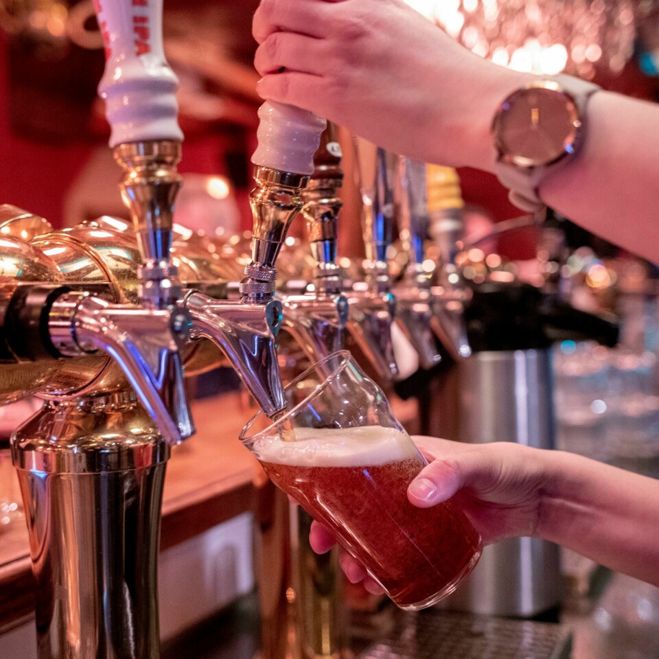 STRENGT: For 100 år siden siden var nok strenge regler viktig for å redde folk fra å drikke for mye alkohol. Men nå velger flere å drikke alkoholfritt. Fordi de har lyst på det. Bildet er av en øl som blir tappet i et glass. En hånd holder glasset og en annen i spaken på tappetårnet der ølen kommer ut. Bildet er fra en bardisk.