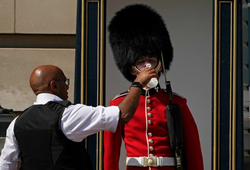 VANN: En politibetjent gir vann til en soldat i London mandag. Bildet viser en politibetjent som gir vann til en soldat i London mandag. Foto: Matt Dunham / AP