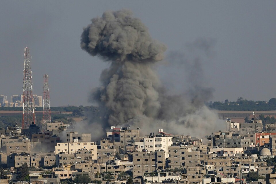 BOMBING: Flere bomber har truffet hus i Gaza. Her er en av dem. Nå er det blitt enighet om våpenhvile. Røyk stiger opp fra et angrep på en boligbygning på Gazastripen søndag. Foto: Adel Hana / AP / NTB