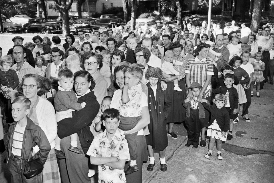 1953: Foreldre og barn venter på å få vaksine mot polio i 1953. Lange køer med barn og voksne ventet på å få den nye poliovaksinen ved en skole i Elmira i New York i juli 1953, på et tidspunkt da mange barn i USA ble smittet. Mange ble delvis lammet, og en del av dem døde. Foto: Paul E. Thomson / AP / NTB