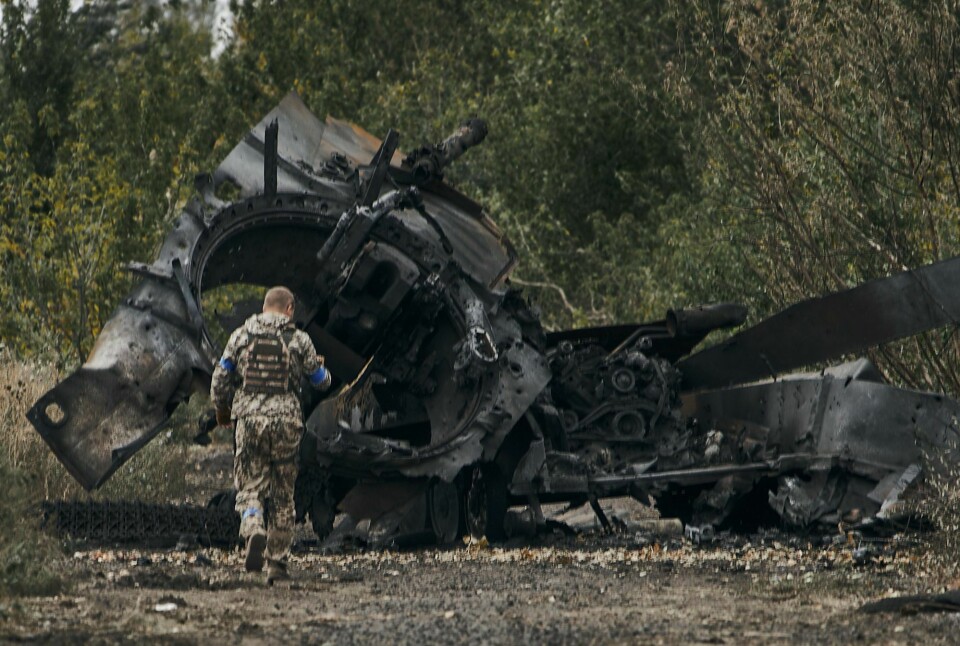 TILBAKE: Soldater fra Ukraina er tilbake i store deler av Kharkiv. Det skjer etter at det de siste dagene har vært harde kamper om makta i fylket. Bildet er av en ukrainsk soldat som går forbi restene av en russisk tanks som er sprengt og utbrent. I bakgrunnen er det skog. Bildet er fra veien ved byen Balakleya i Kharkiv. Foto: AP / NTB