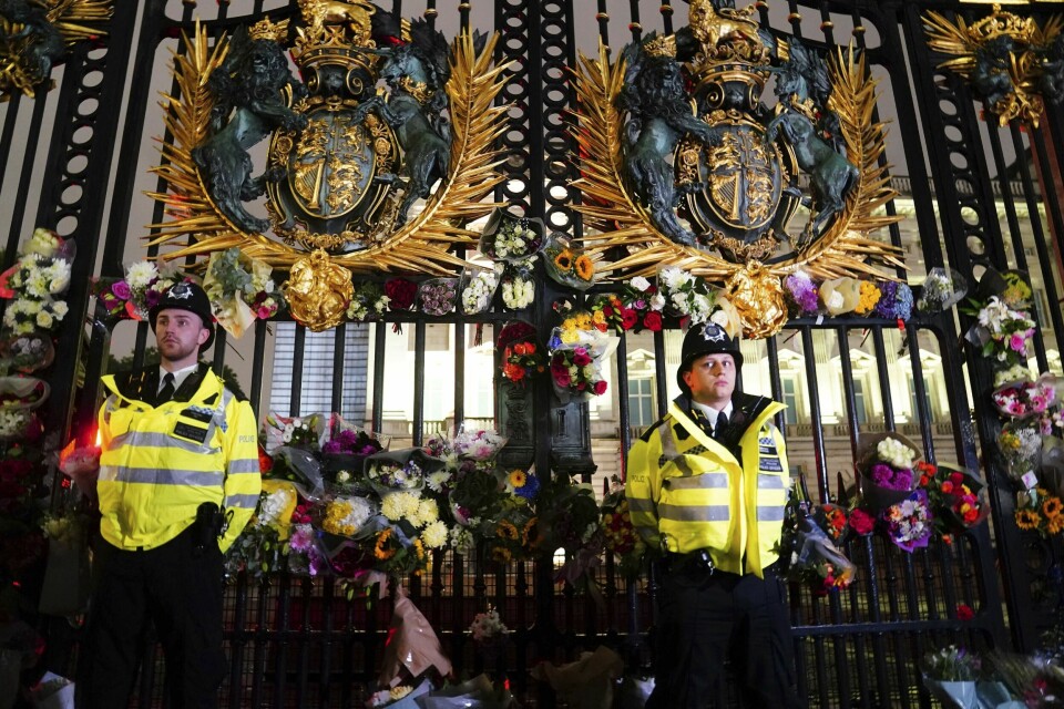 SORG: Folk har lagt ned blomster ved Buckingham Palace i London. Dronning Elizabeth II døde torsdag. Hun var dronning i 70 år. Victoria Jones/PA via AP) Politibetjenter står blant blomster og lapper som er blitt lagt ned utenfor Buckingham Palace etter nyheten om dronningens bortgang. Foto: Victoria Jones / PA via AP / NTB