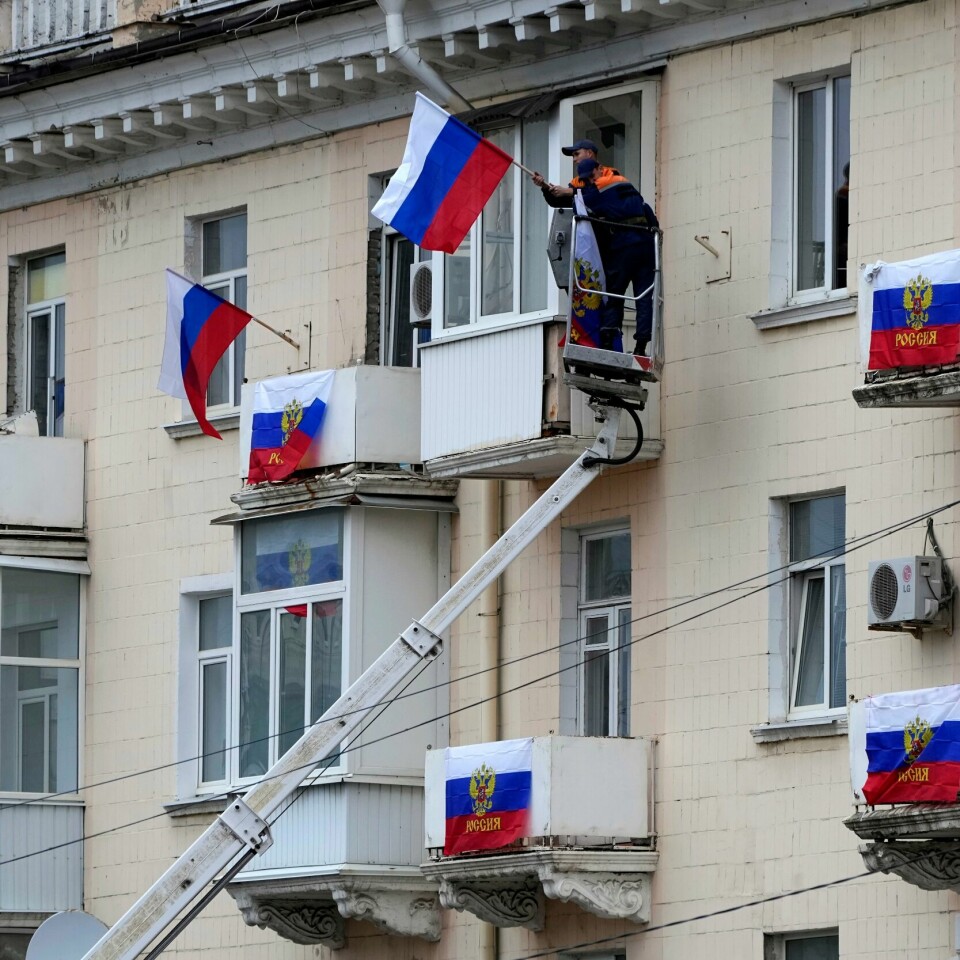 FLAGG: Arbeidere henger opp russiske flagg på en bygning i Luhansk i Ukraina. Bildet viser at arbeidere henger opp russiske flagg på en bygning i Luhansk i Ukraina