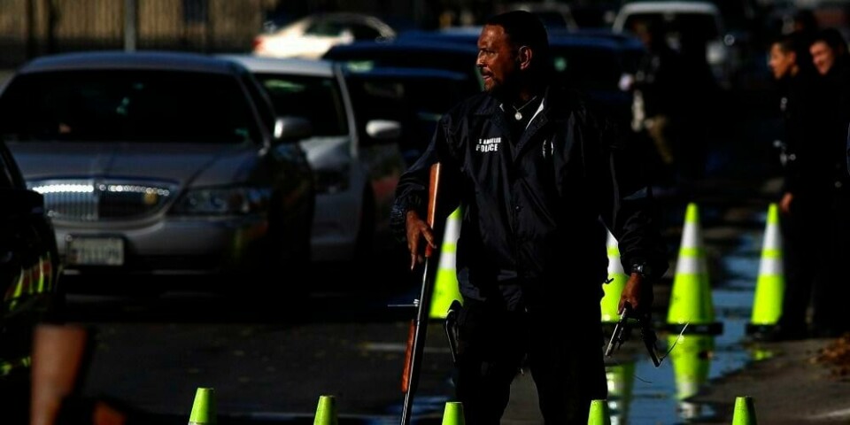 VÅPEN: Politifolk samler inn våpen fra folk som venter i kø i bilene sine i Los Angeles i USA. Torsdag ble det lange køer da mange valgte å levere inn våpen. De slipper spørsmål fra politiet når dem frivillig. Det skjer etter skytingen ved skolen Newtown i delstaten Connecticut. 20 barn og seks voksne ble drept i skytingen.