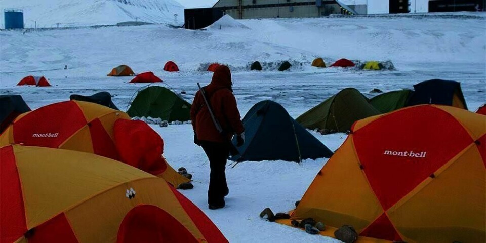 VAKT: Juliane Opielka fra Tyskland går vakt mellom teltene på Svalbard. Det kan komme isbjørn. Her er mange folk fra hele verden. De skal se solformørkelsen.