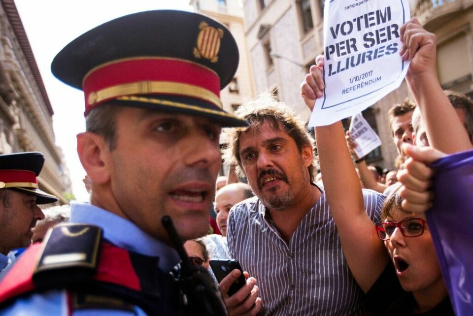 SINTE: Stemningen er ikke god før valget i Catalonia søndag. Spanske politimenn forsøker å stanse folk fra å stemme. Bildet viser folk som roper til en spansk politimann i Catalonia.