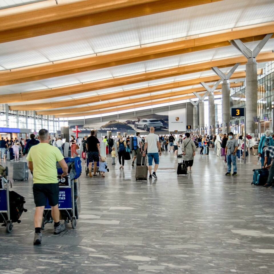 REISE: Mange har reist fra Norge og til varmere land. Flere av de kan møte krav om karantene når de kommer hjem til Norge. Bildet er av folk som går gjennom hallen på Oslo Lufthavn. De har bagasje på traller. Noen står ved skjermer for å sjekke inn og finne flytider. Foto: Hanna Johre / NTB