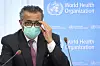 Bildet er av WHO-sjef Tedros Ghebreyesus. Han er kledd i dress og har to mikrofoner foran seg. Bak ham er det en blå vegg. Navnet til Verdens helse-organisasjon (World Health Organization) er skrevet med hvite bokstaver på veggen. Foto: Laurent Gillieron / AP / NTB