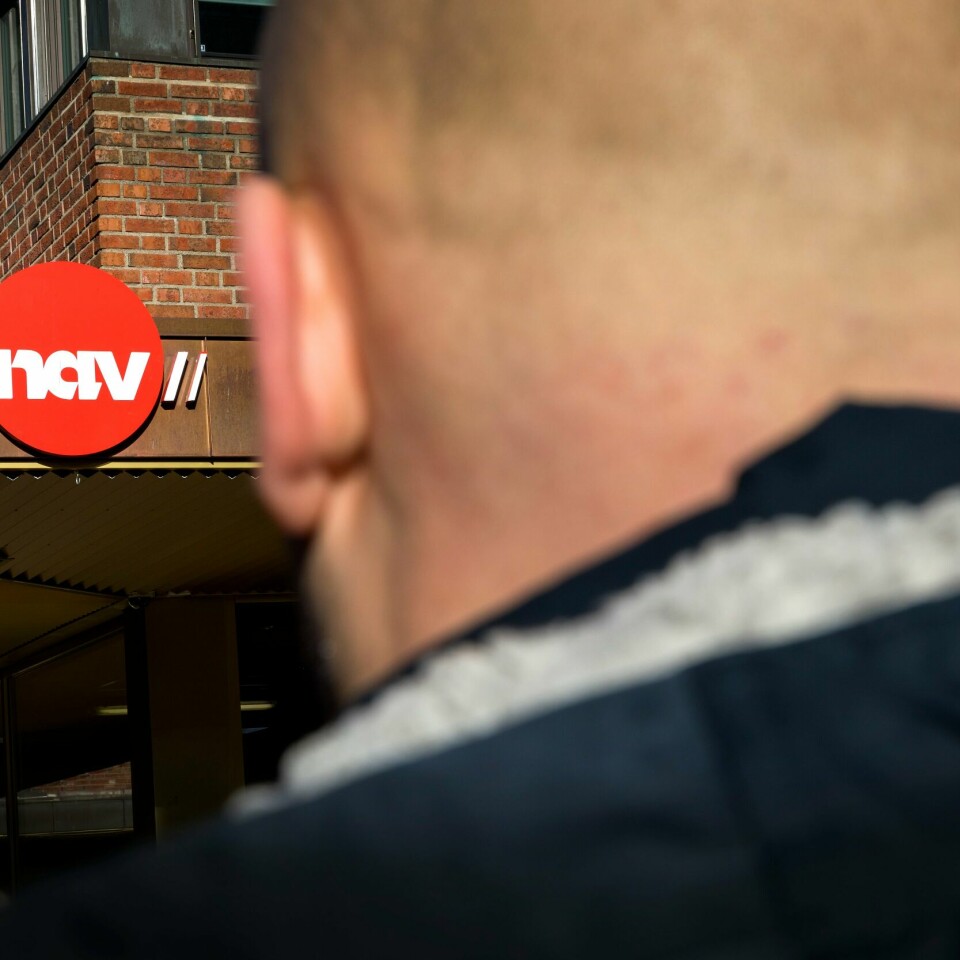 NAV: Staten kan bli saksøkt etter Nav-skandalen. Det sier organisasjonen Nav-it. Bildet er av en mann som ser på en murbygning med Nav-logoen. Han har kort hår, og bildet er tatt bakfra. Foto: Gorm Kallestad / NTB