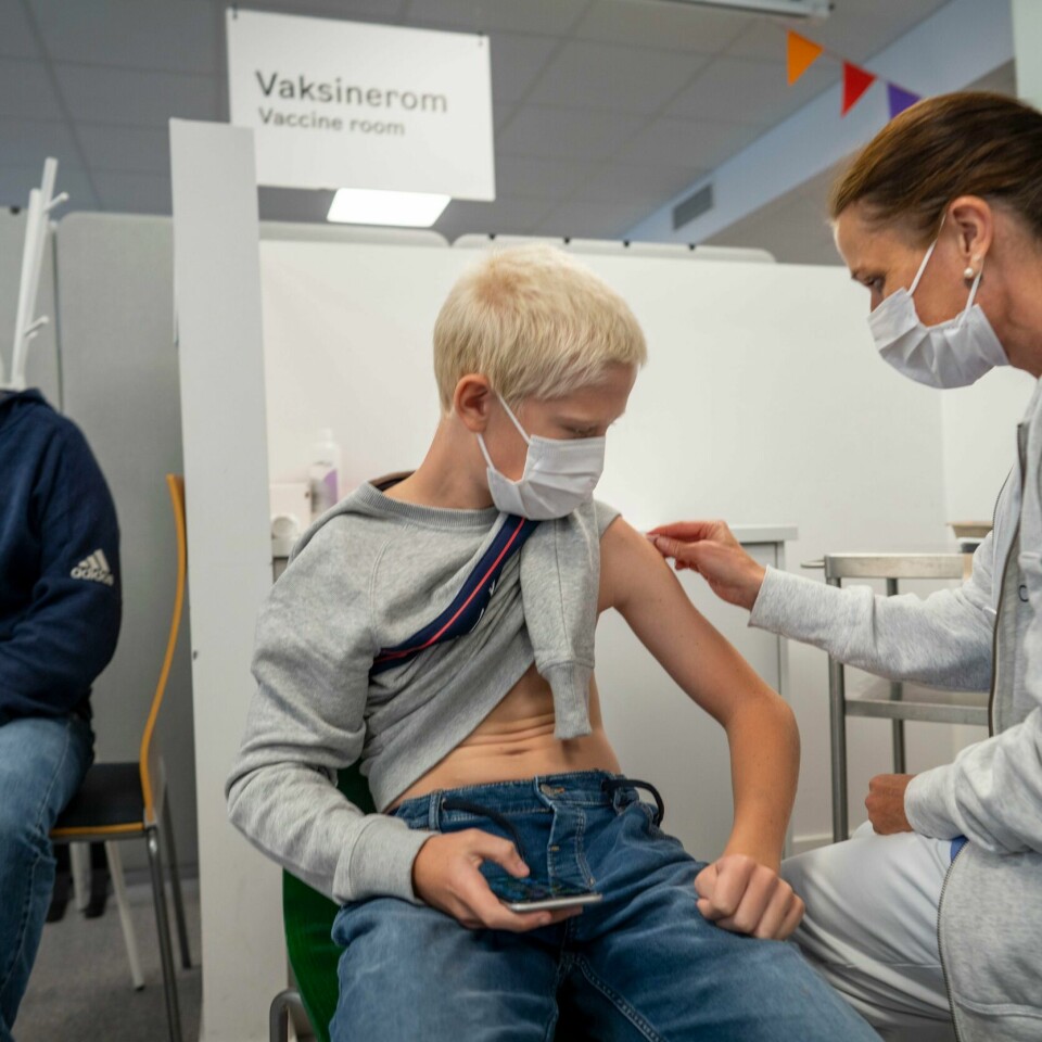 VAKSINE: Ungdommer på 16 og 17 år skal få tilbud om korona-vaksine. Her sitter Eirik Lyngstad og får første dose av Pfizer-vaksinen. Han er kun 13 år og har et svekket immunforsvar. Derfor får han vaksine tidligere enn andre. 13-åringen får første dose med Pfizer-vaksine på Bjerke vaksinesenter i Oslo mens pappa Roy Ove følger lettet med. Foto: Heiko Junge / NTB