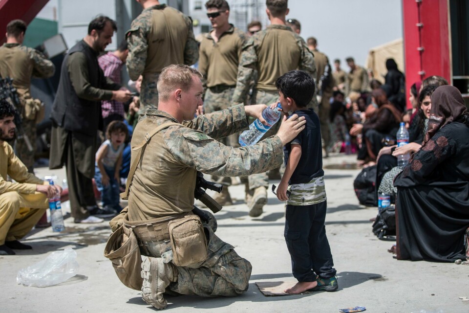 EVAKUERING: Flere ønsker seg bort fra Afghanistan. Her gir en amerikansk soldat vann til en liten gutt. En amerikansk soldat gir en gutt vann under evakueringen på flyplassen i Kabul. Foto: Samuel Ruiz / Den amerikanske marinen / AP / NTB.