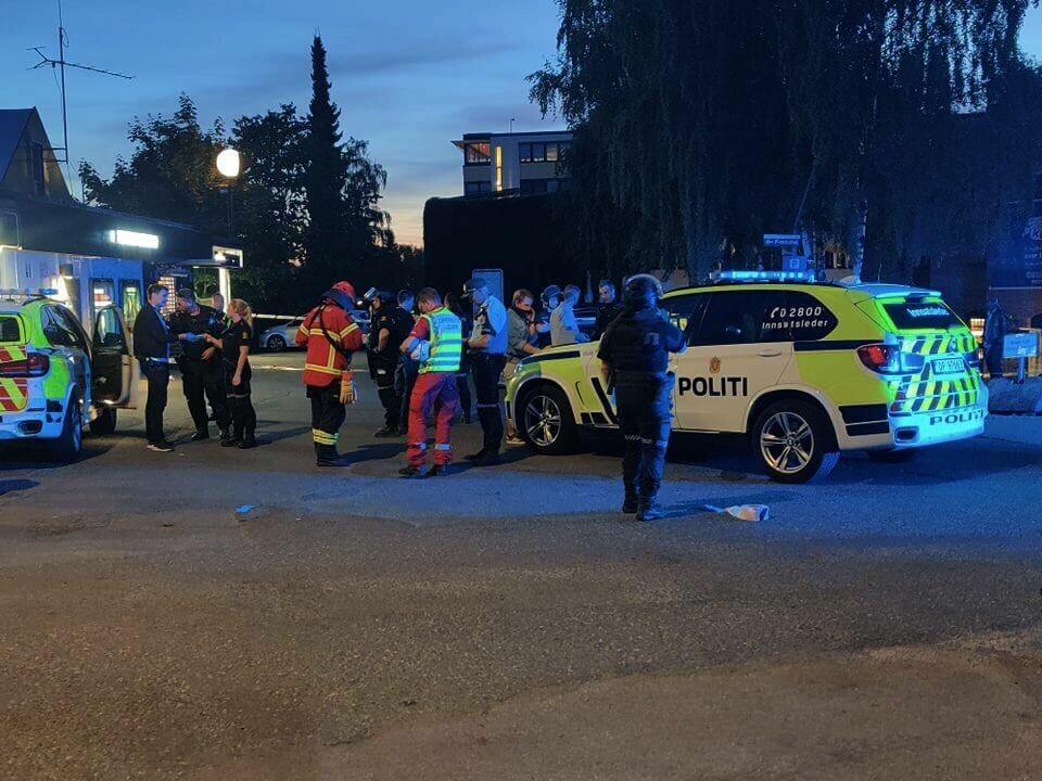 POLITI: Politiet bruker mye ressurser på å finne én eller flere gjernings-personer. Én person skal ha blitt skutt og er alvorlig skadd. Flere politi og brannmenn samlet rundt en politibil.