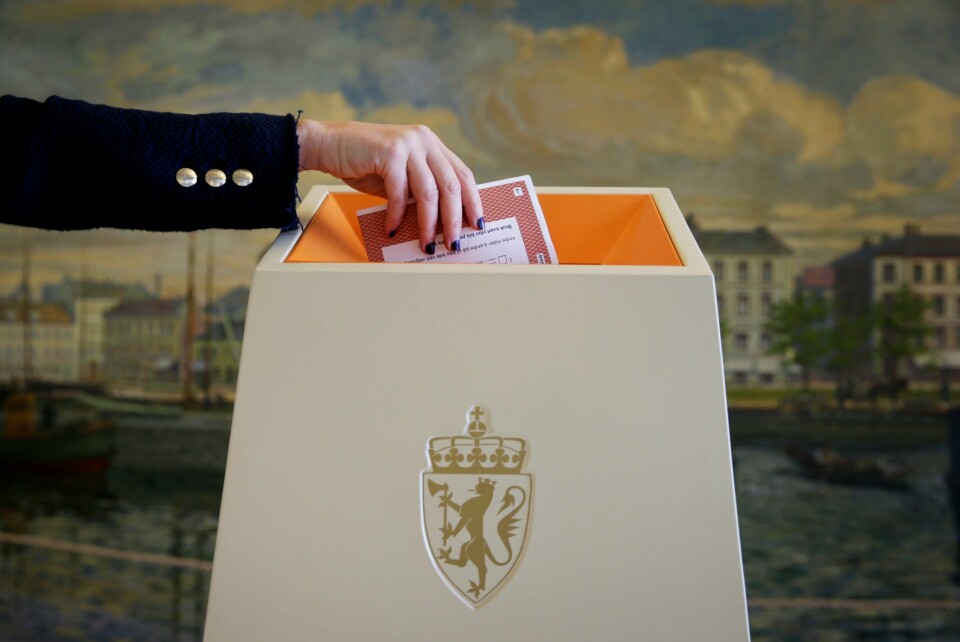 JEVNT: Få stemmer kan bety mye for noen kandidater og partier etter valget i år. I noen fylker kan under 100 stemmer endre hvem som blir valgt inn. Bildet er av en arm som putter en stemmeseddel i en valgurne. I bakgrunnen er det en vegg med et påmalt bylandsskap. Foto: Håkon Mosvold Larsen / NTB / NPK