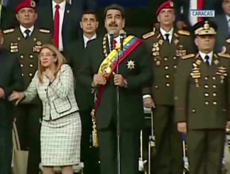 EKSPLOSJON: Det smalt mens Venezuelas president Nicolás Maduro (i midten) holdt en tale. Hans kone Cilia Flores rykket til og kikket opp etter det første smellet.