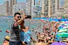 Bildet viser et par som tar selfie på stranda i Benidorm i Spania.