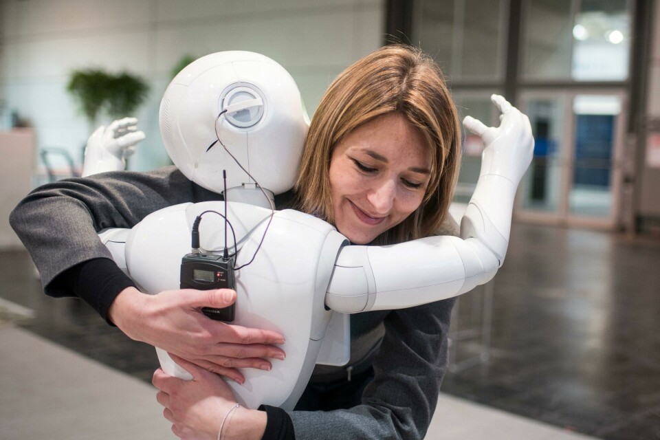 KLEM: Roboten Pepper gir deg gjerne en klem. Selskapet SoftBank Group fra Japan har laget den. Bildet viser roboten Pepper som gir en dame en klem.
