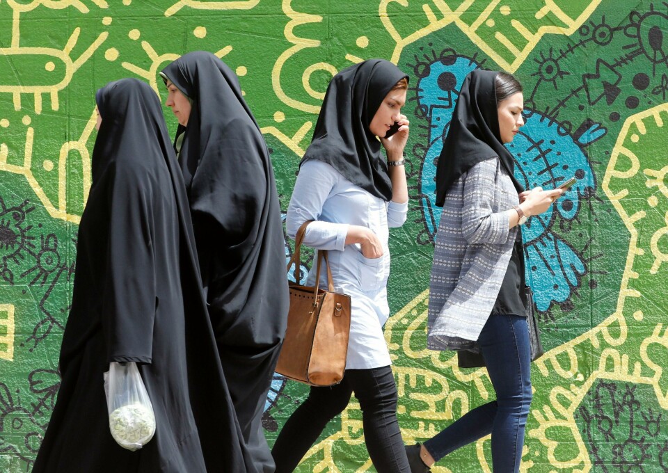IRAN: Kvinner skal dekke håret i Iran, sier loven. Bildet er fra hovedstaden Teheran i april i år. Bildet viser kvinner kledd i hijab som snakker i telefonen. To andre kvinner i heldekkende plagg går andre veien.