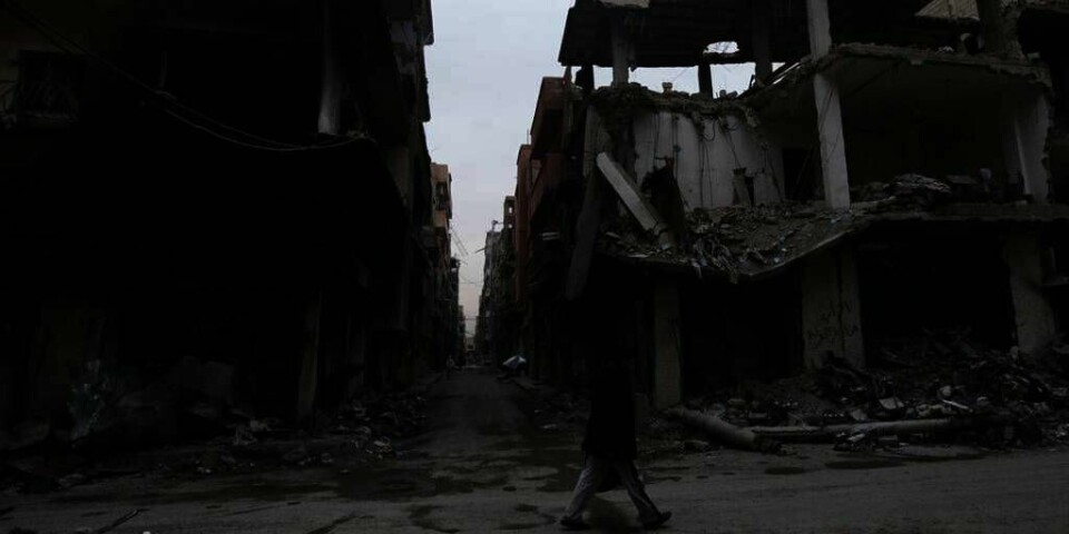 FUNNET: De to norske søstrene som har vært savnet i Syria, er funnet. Den er ene er skadd. Her går en mann forbi noen ødelagte bygninger i den syriske byen Deir al-Zor.