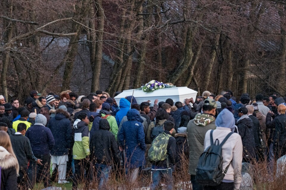 UNGDOMMER: Jakob Hassan ble bare 14 år gammel. Her blir kisten hans båret i begravelsen. Bildet viser ungdommer i begravelsen til Jakob Hassan. Bildet er tatt fra avstand. Midt i bildet bæres en hvit kiste.