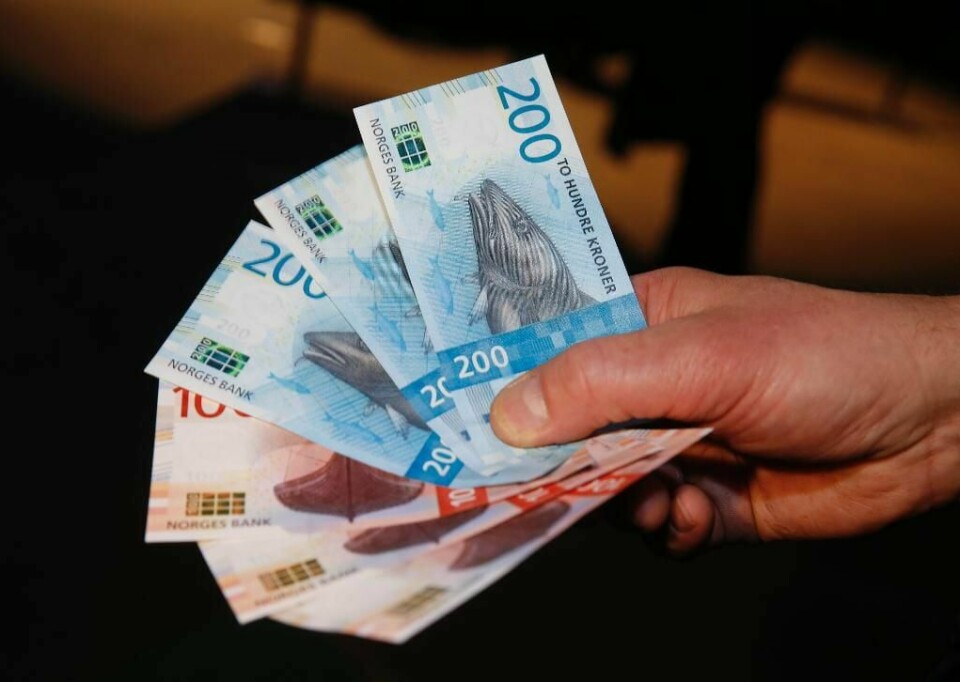 PENGER: Ikke falske eller utenlandske. Dette er de nye norske hundrelappene og tohundrelappene.Bildet viser en hånd som holder tre hundrelapper og tre tohundrelapper. Vi ser bildet av en torsk på tohundrelappen som ligger øverst.