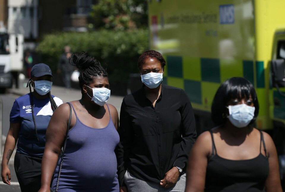 MASKER: Folk har masker på seg i nærheten av brannen. Bildet viser fire personer med hvite masker foran munn og nese.
