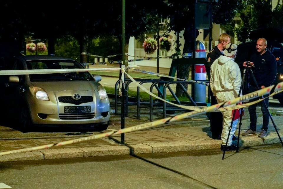 DREPT: Tre personer ble knivstukket i Sarpsborg. Det skjedde natt til onsdag. To ble kritisk skadd. Den ene er død. Politiet på stedet hadde våpen. En mann er pågrepet i saken. Bildet viser tre politifolk, som står ved et område som er sperret av. Det står også en bil uten skilter på stedet.