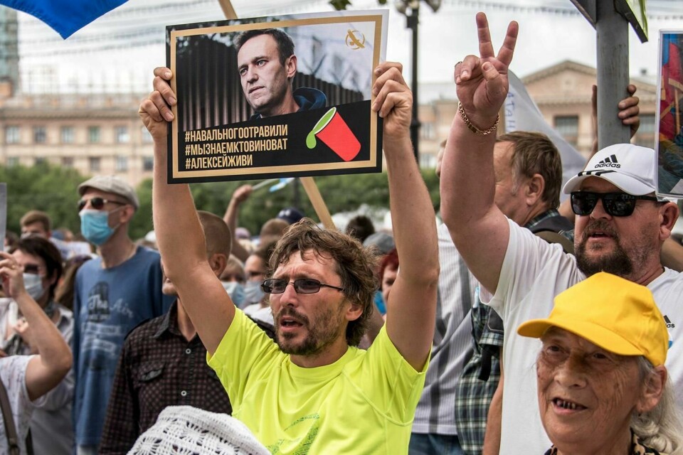 STØTTE: Den russiske opposisjons-politikeren Aleksej Navalnyj får mye støtte. Han kjemper for livet på sykehus. En demonstrant holder opp en plakat av ham.