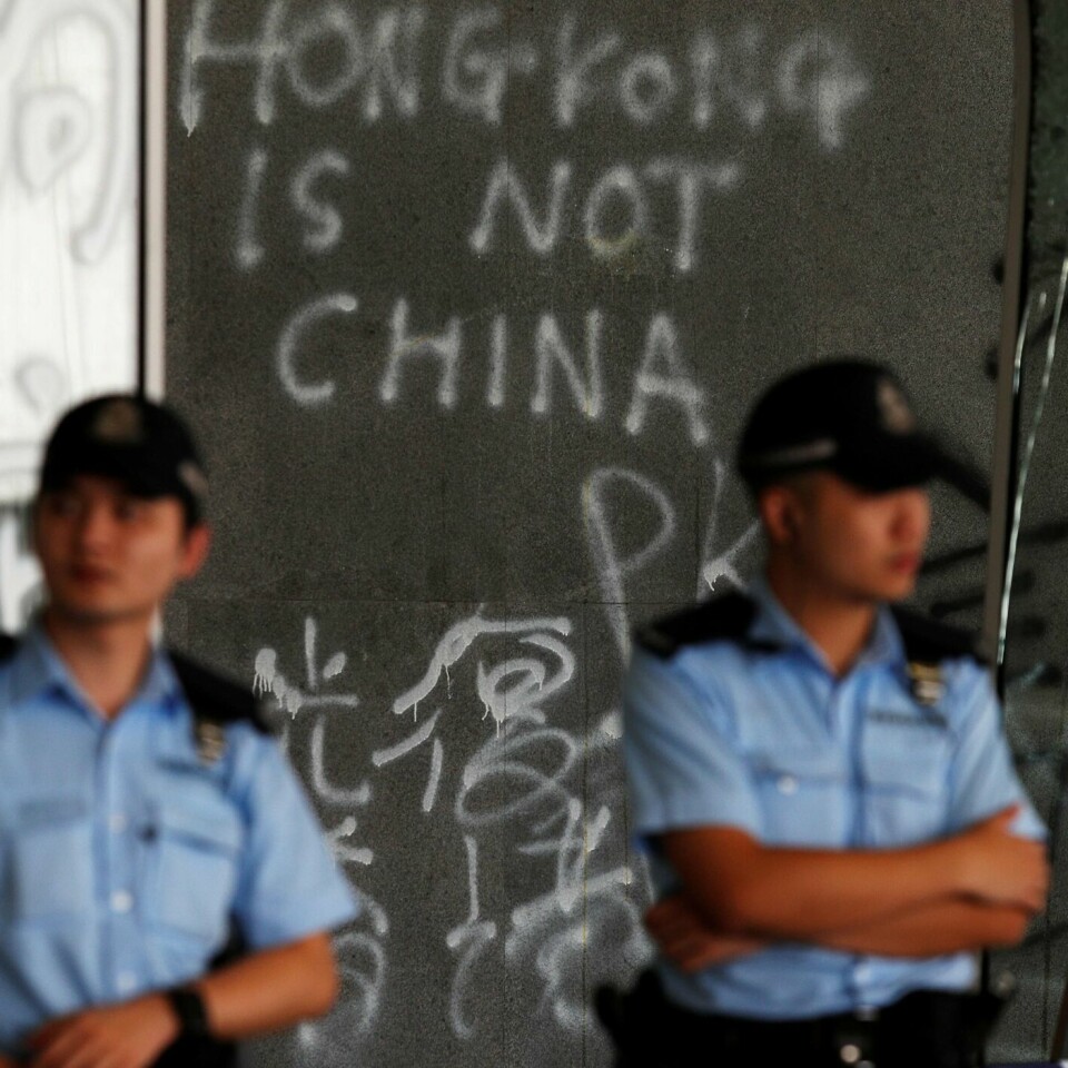 ANGREP: Demonstranter angrep bygningen til de folkevalgte i Hongkong. Det skjedde mandag 1. juli. Her passer politimenn på bygningen. Noen har skrevet «Hongkong er ikke Kina» på veggen.
