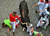 Bildet viser en okse som stanger mennesker i gatene i Pamplona.