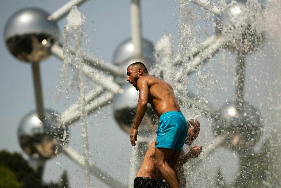 VARMT: To menn kjøler seg ned i en fontene ved skulpturen Atomium. Det er i Brussel i Belgia.