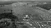 Bildet viser Woodstock-festivalen fra lufta. Det er mange mennesker og telt på bildet.