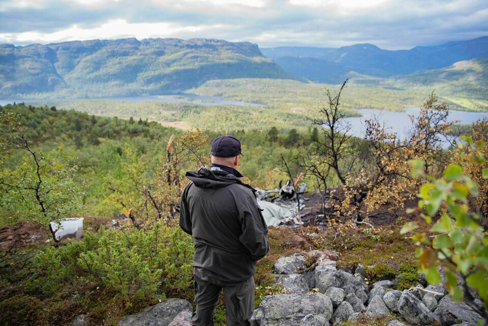 ØDELAGT: Rester av helikopteret ligger på kanten av en liten skrent i Alta. En politimann står rett ved. Seks personer døde i ulykken lørdag.