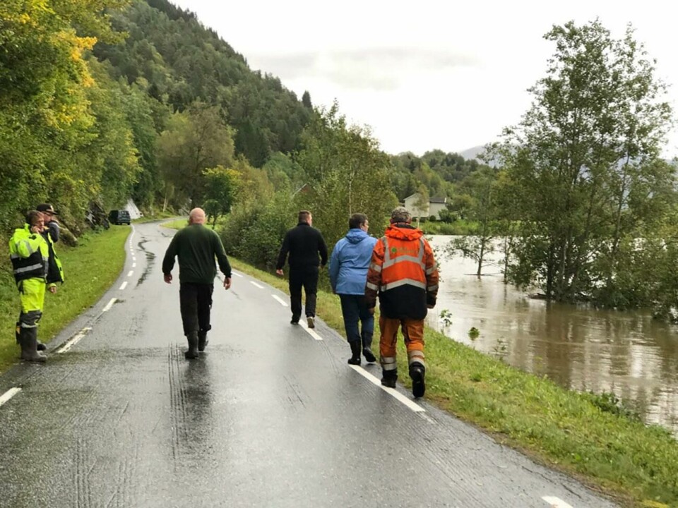 FLOM: Elva Surna i Møre og Romsdal har gått over sine bredder. Over 100 sauer er tatt av vannet. Bildet viser folk som går på veien langs Elva Surna i Møre og Romsdal.
