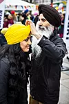 Bildet viser en eldre mann i turban som surrer en turban rundt hodet på en kvinne.
