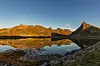 Bildet viser spisse fjell som speiler seg i vannet. Bildet er fra Lofoten i Nordland.