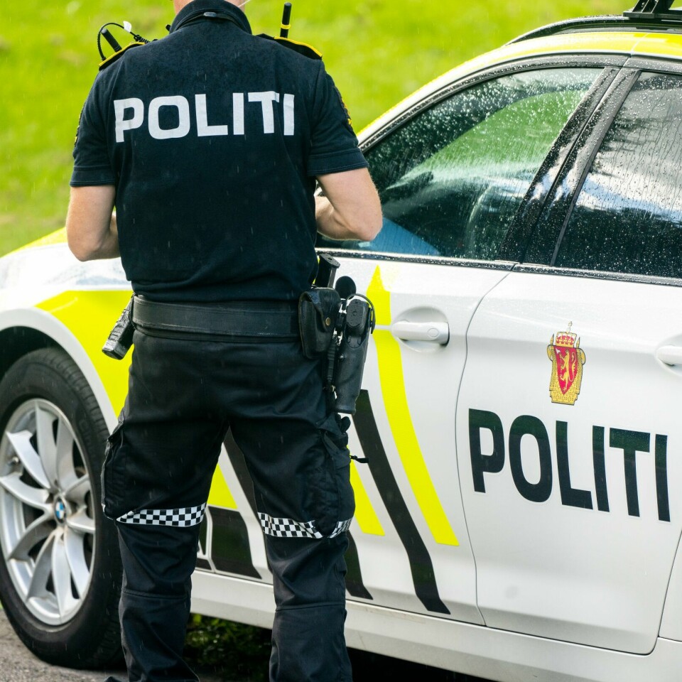 VÅPEN: Politiet fortsetter å bære våpen. Bildet viser politimann med våpen ved en politibil.