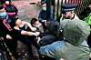 Bildet er av en mann som blir dratt i to ulike retninger av politi og ansatte ved Kinas konsulat i Manchester i England. Foto: Matthew Leung / The Chaser News / AP / NTB