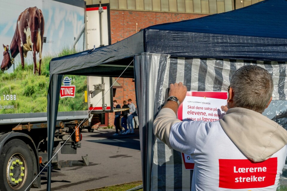 STREIK: Lærere var en av mange yrkesgrupper som var i streik i 2022. Bildet er av en streikende lærer som henger opp informasjon på et telt utenfor en skole. Foto: Gorm Kallestad / NTB