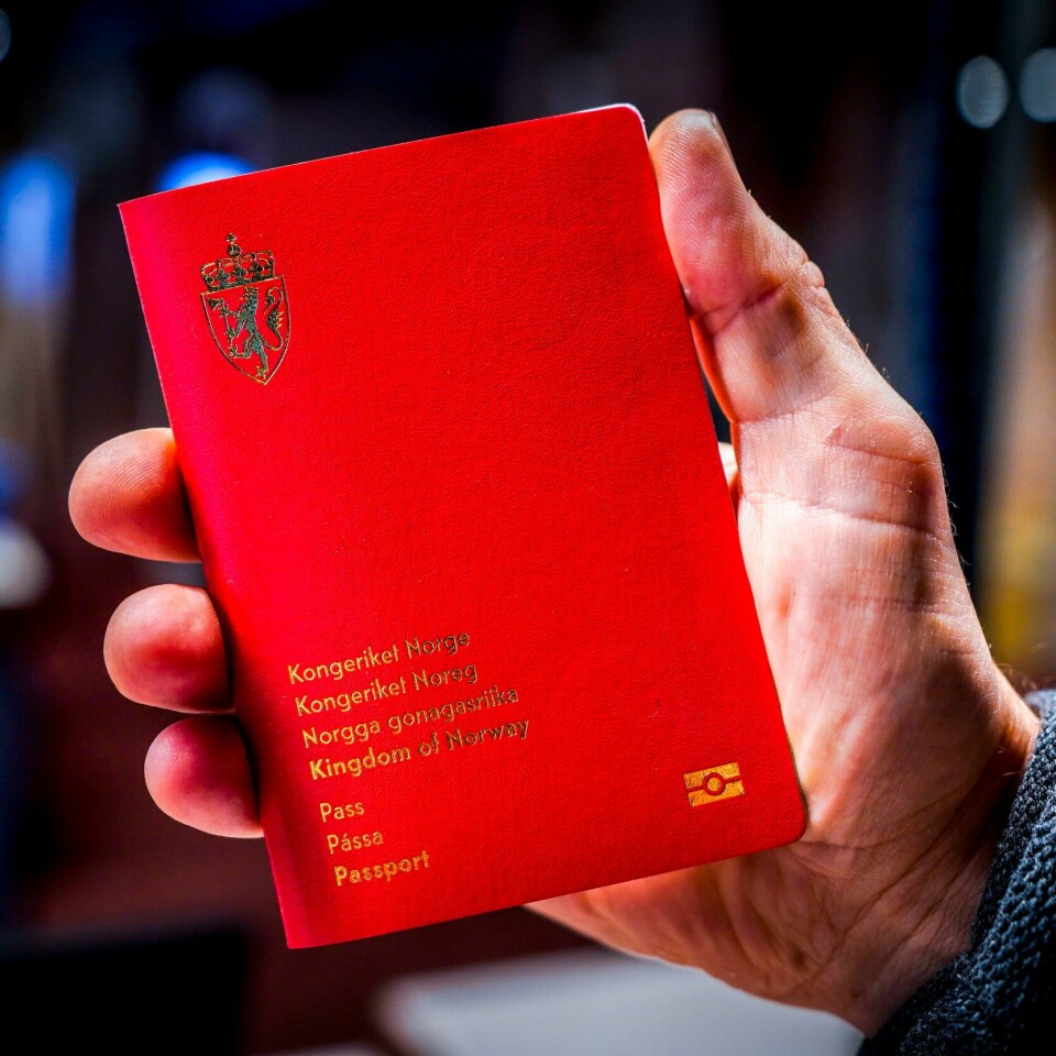 PASS: Slik ser de nye norske passene ut. Om statlig ansatte fortsetter å streike, kan det bli vanskelig å få et nytt. Bilde av en hånd som holder det nye norske (røde) passet. Det står kongeriket Norge på flere språk på passet.