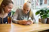 Bildet viser unge jenter som drikker iste og scroller på mobilen. Foto: NTB
